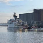 two John McLoughlin tug boats on the water with a larger boat